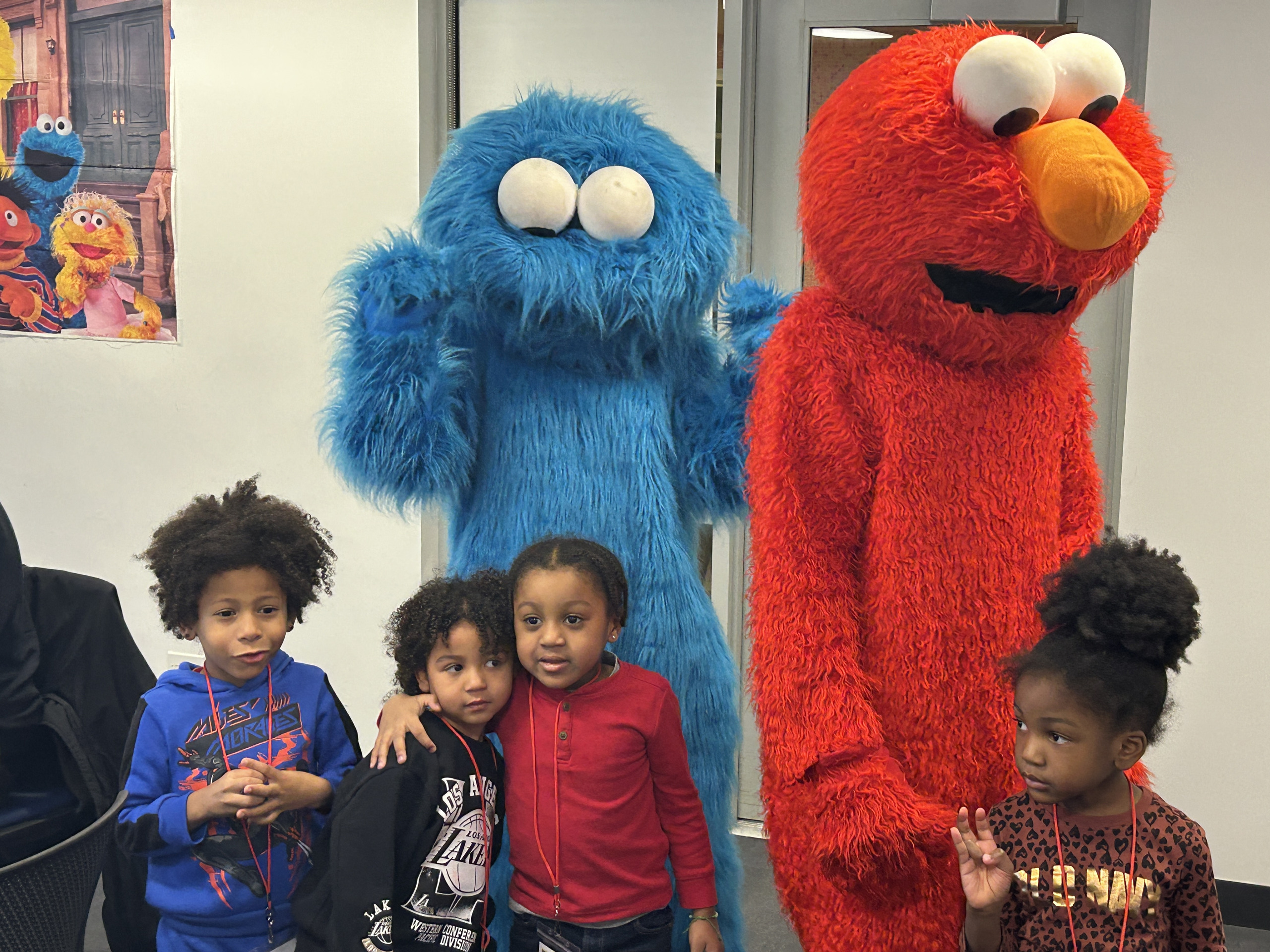 Four children posing with Cookie Monster and Elmo